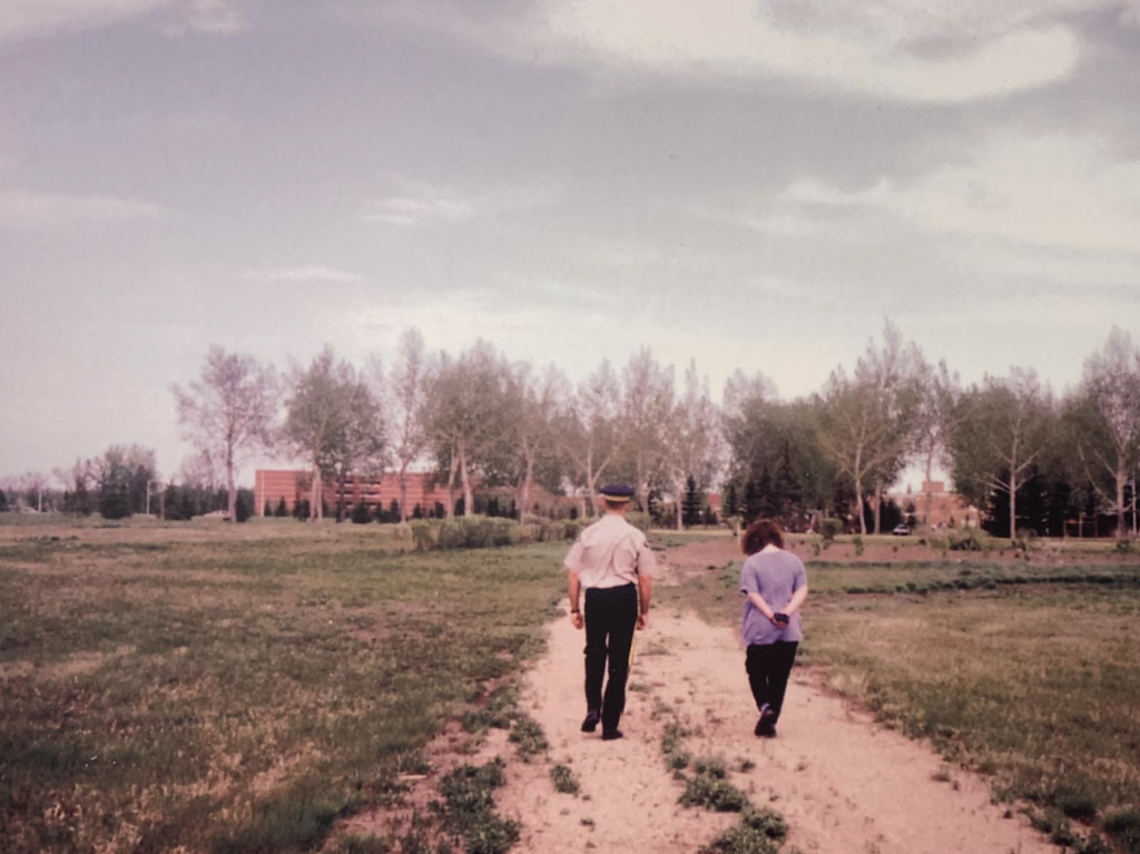a new RCMP recruit and his wife walk down a dirt road 